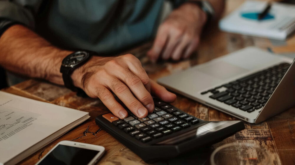 Pessoa usando calculadora em mesa de trabalho