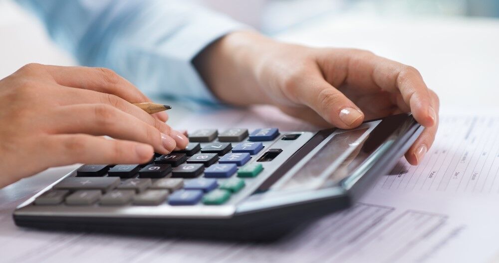 Pessoa usando calculadora em documentos financeiros
